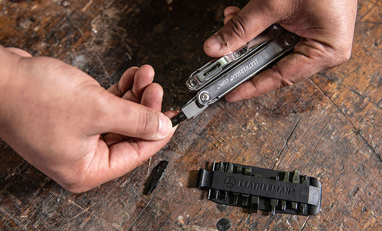 Man replacing a bit from Leatherman Bit Kit on Leatherman Curl over wood table